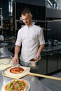 Male chef spreading tomato paste on pizza base