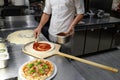 Male chef spreading tomato paste on pizza base