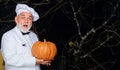 Male chef in uniform with pumpkin. Autumn recipes concept. Useful vegetables. Happy halloween. Bearded cook in chef hat