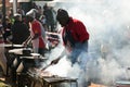 Male chef vendor working a BBQ Grill at hotdog stall at farmer`s market