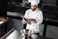 Male chef with wok at kitchen restaurant. Concentrated man with pepperbox. Royalty Free Stock Photo