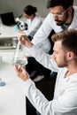 Male chemists in lab coats examining reagent in flask Royalty Free Stock Photo