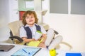 Male child playing business, holding a cup in his hands, riding on an office chair, career. Smiling little boss in the Royalty Free Stock Photo