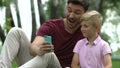 Male and child taking selfies, mugging for camera, family leisure with gadgets