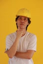 Male civil engineer or architect with yellow helmet and wear white T-shirt on yellow background. and expressing thoughts