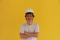 Male civil engineer with white helmet and wear white T-shirt on yellow background. Standing and cross one`s arm