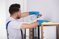 Male Cleaner Cleaning Shelf At Workplace