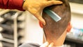 Male client getting a haircut by the hairdresser with an electric shaver in a barbershop Royalty Free Stock Photo