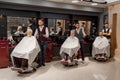 Male clients sitting in hairdresser chairs covered with haircut. Royalty Free Stock Photo