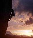 Male silhouette rock climbing, doing next step on cliff. Dark purple cloudy sky on background with copy space. Low angle Royalty Free Stock Photo