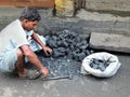 A male coal breaker breaking coal with hammer.