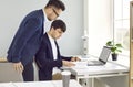 Male colleagues are reviewing document entries together while working in company's business office.