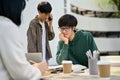 A male college student focuses on reading a book while working on a school project with his friends Royalty Free Stock Photo