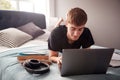 Male College Student Lies On Bed In Shared House Working On Laptop Royalty Free Stock Photo