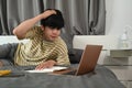 Male college student lying on bed and working with laptop. Royalty Free Stock Photo