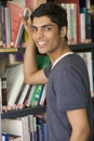 Male college student reaching for a library book Royalty Free Stock Photo