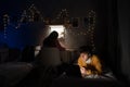 Male college student wearing headphones lies on bed in shared house working on laptop and girl while studying on Royalty Free Stock Photo