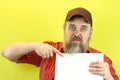 Male construction worker holding blank advertising board. Construction worker with poster. A rude, bearded, stern man in a red shi Royalty Free Stock Photo