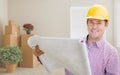 Male Construction Worker In Room With Boxes Holding Roll of Blue