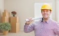 Male Construction Worker In Room With Boxes Holding Roll of Blue