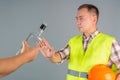 A male construction worker in work clothes refuses a proffered bottle of strong alcohol. Refusal to drink at work Royalty Free Stock Photo