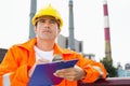 Male construction worker writing on clipboard at industry