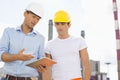 Male construction workers discussing over digital tablet at industry