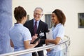 Male Consultant Meeting With Nurses Using Digital Tablet