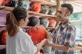 Male consumers smile when choosing a helmet served by a beautiful woman shopkeeper
