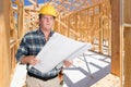 Male Contractor With House Plans Wearing Hard Hat Inside New House Construction Framing Royalty Free Stock Photo