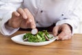 Male cook chef decorating garnishing prepared salad dish on the plate in restaurant commercial kitchen. Royalty Free Stock Photo