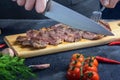 A male cook cuts a steak into portions. Fresh meat is medium rare