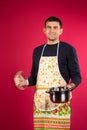 Male cook with a saucepan on pink background. The concept of gender neutrality