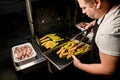 Male cook shifts fried slices of zucchini on metal tray Royalty Free Stock Photo