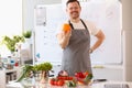 Male cook teacher in apron holds an orange and fresh vegetables and fruits on table Royalty Free Stock Photo