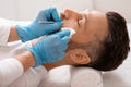 Cosmetician using blackhead remover for cleaning man face in spa