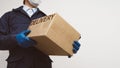 Male courier with a box in a protective mask and gloves. Home delivery of food and medicine during a pandemic covid-19 Royalty Free Stock Photo