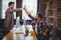 Male coworkers high fiving in office