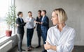 Male Coworkers Whispering Behind Back Of Unhappy Businesswoman In Office Royalty Free Stock Photo