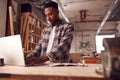 Male Craftsman In Carpentry Workshop For Bamboo Bicycles Doing Accounts On Laptop