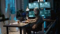 Male criminal wearing mask and hood to hack computer system