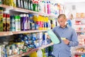 Male customer looking goods with shopping list in household shop Royalty Free Stock Photo