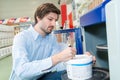 Male customer selecting paint can in houseware department