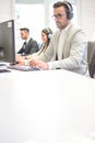 Male customer support operator with headset working on computer in office. Copy space on table. Royalty Free Stock Photo