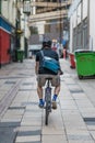 Male cyclist with a helmet on rides through a back alley in Sheffield City Centre