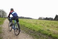 Male cyclist pauses on bike in open countryside, back view Royalty Free Stock Photo