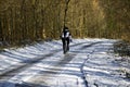 A male cyclist riding along a snow covered countryside road