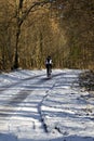 A male cyclist riding along a snow-covered countryside road in winter Royalty Free Stock Photo