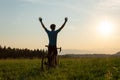 Male cyclist riding a bike with arms raised, in a victory pose