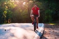 Male cyclist riding his bike on sunset on a road through deep woods. Extreme biker no safety equipment